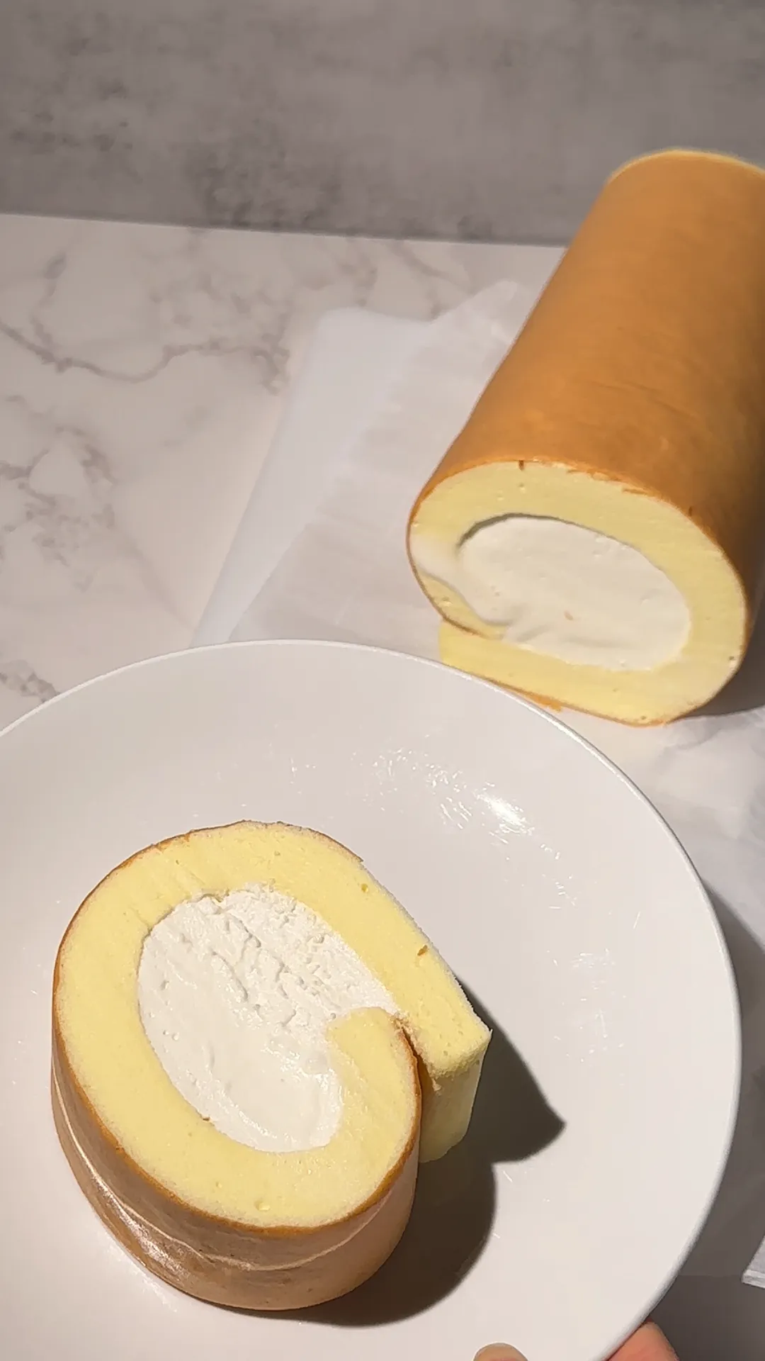 A soft gluten-free cloudy cake roll rolled around lightly whipped cream